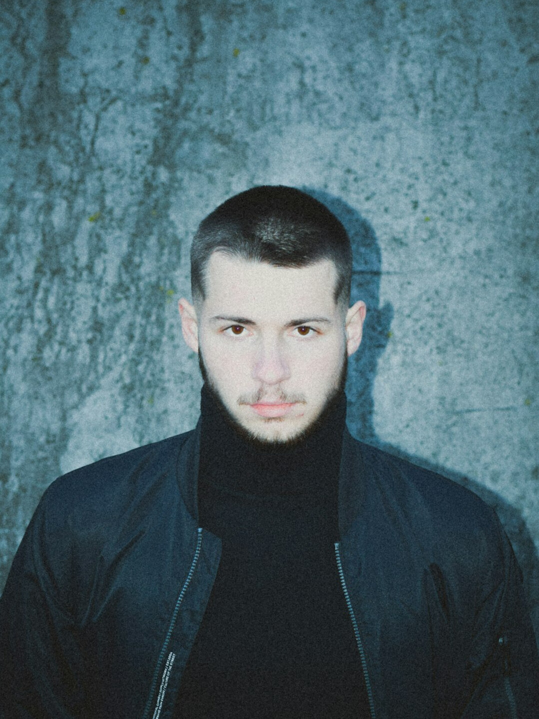 Studio portrait of a man with short beard wearing a navy jacket